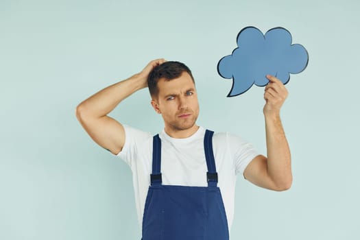 In blue uniform. Man standing in the studio with empty signs for the text.