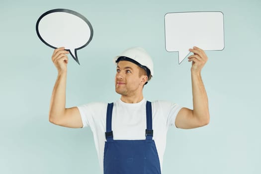 In white protective hat. Man standing in the studio with empty signs for the text.