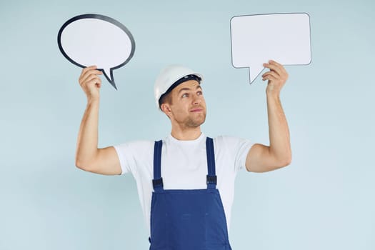 In white protective hat. Man standing in the studio with empty signs for the text.