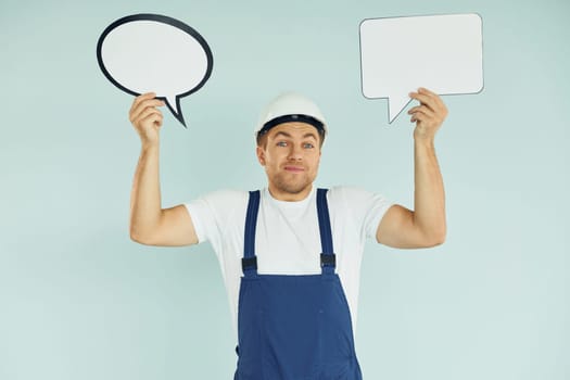 In white protective hat. Man standing in the studio with empty signs for the text.