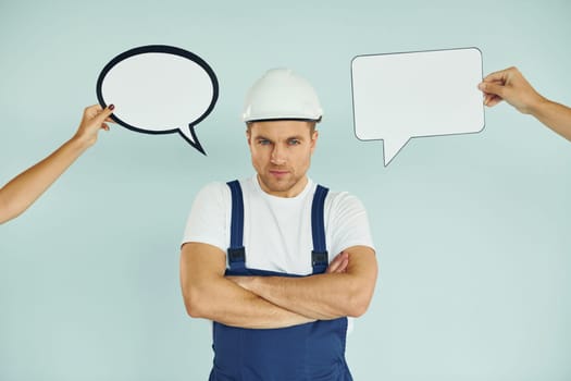 Worker is thinking. Man standing in the studio with empty signs for the text.