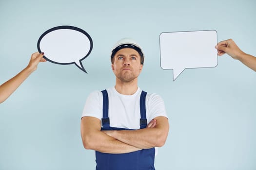 Worker is thinking. Man standing in the studio with empty signs for the text.