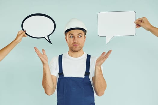 Worker is thinking. Man standing in the studio with empty signs for the text.