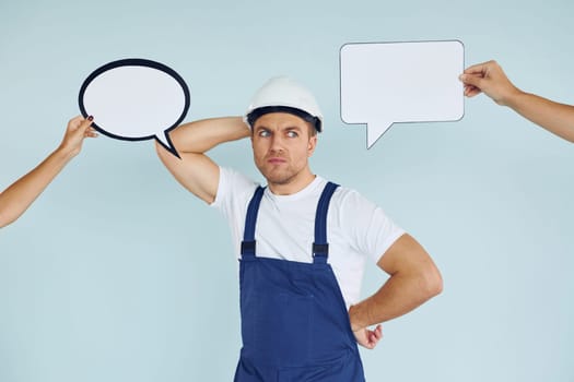 White hard hat and blue uniform. Man standing in the studio with empty signs for the text.
