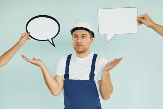 White hard hat and blue uniform. Man standing in the studio with empty signs for the text.
