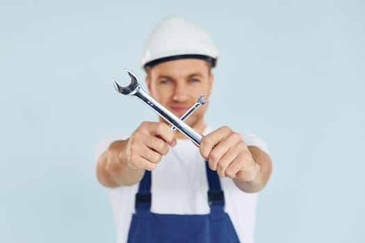 Worker in uniform and hard hat standing in the studio with equipment.