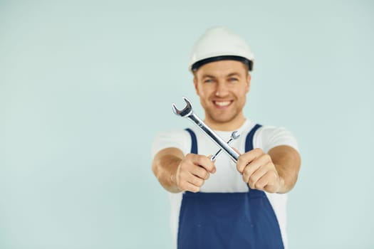 Worker in uniform and hard hat standing in the studio with equipment.