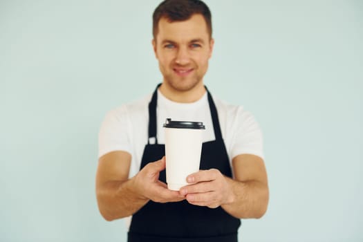 Man in uniform standing in the studio with drink in hands.