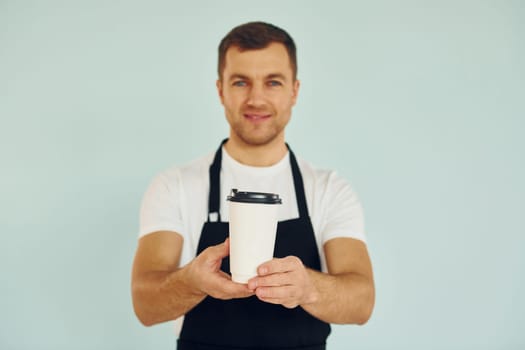 Man in uniform standing in the studio with drink in hands.