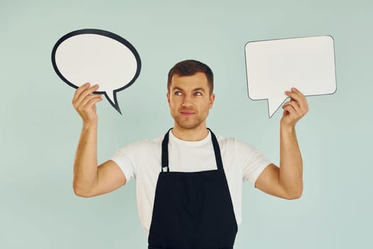 Hard choice between two ideas. Man standing in the studio with empty signs for the text.