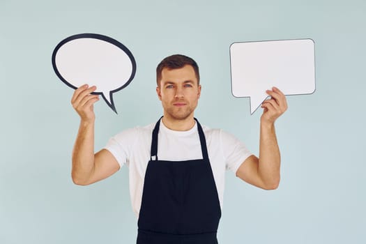 Hard choice between two ideas. Man standing in the studio with empty signs for the text.