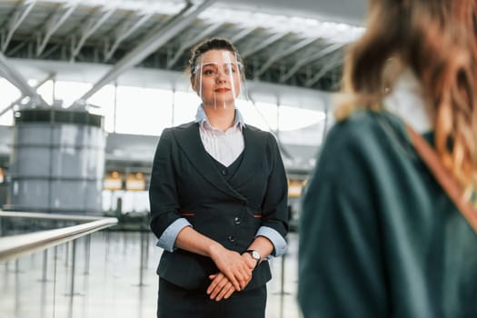 Assistance by woman in formal clothes. Young female tourist is in the airport at daytime.