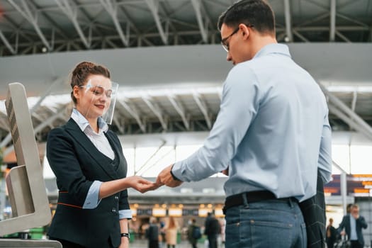 Checking documents. Young businessman in formal clothes is in the airport at daytime.