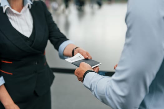 Checking documents. Young businessman in formal clothes is in the airport at daytime.