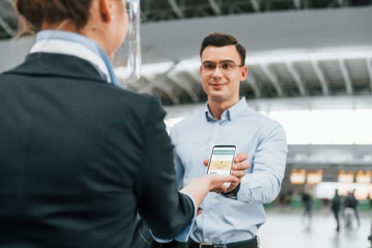 Man showing vaccination certificate. Young businessman in formal clothes is in the airport at daytime.