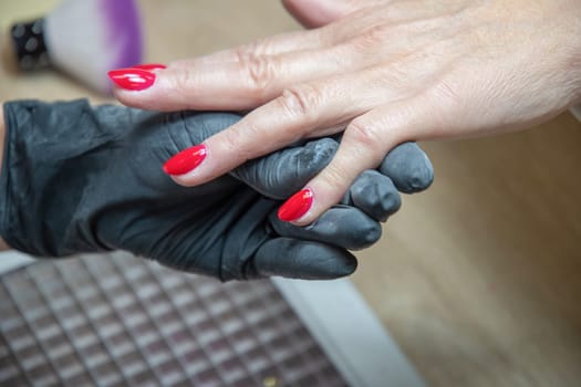 A master manicurist covers the renewed nails of the client with red varnish, Manicure process in beauty salon, High quality photo