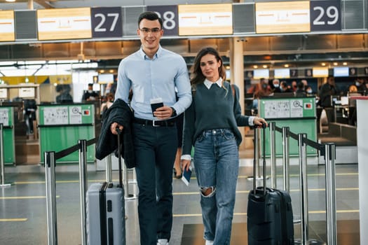 Walking forward. Young couple is in the airport together.