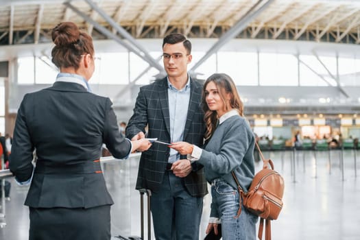 Giving the documents. Young couple is in the airport together.