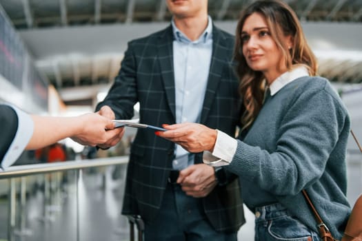 Giving the documents. Young couple is in the airport together.