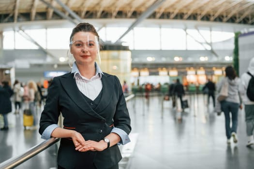 Female aurport worker in formal clothes is standing indoors.