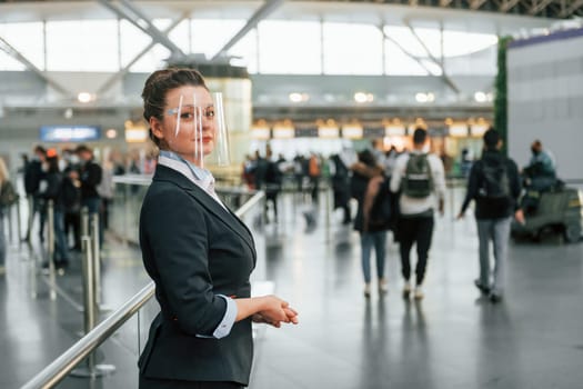 Female aurport worker in formal clothes is standing indoors.