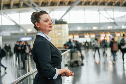 Female aurport worker in formal clothes is standing indoors.
