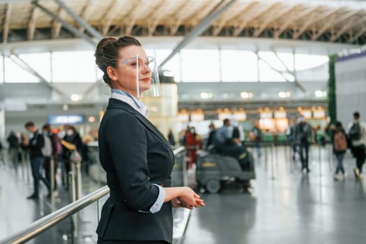 Female aurport worker in formal clothes is standing indoors.