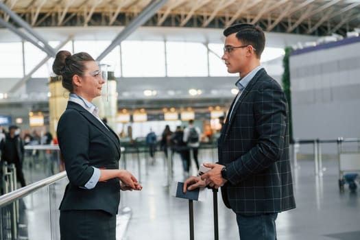 Working with documents. Young businessman in formal clothes is in the airport at daytime.