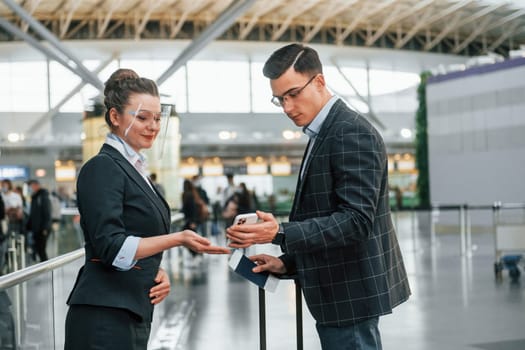 Working with documents. Young businessman in formal clothes is in the airport at daytime.