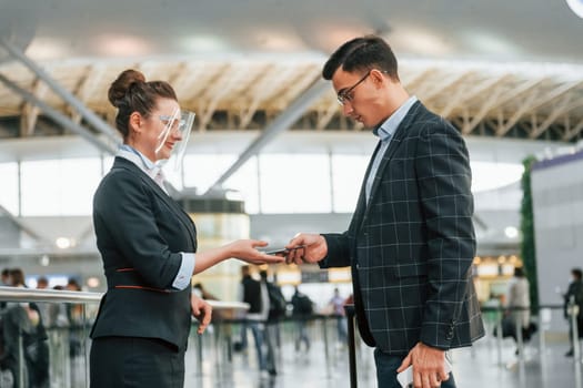 Working with documents. Young businessman in formal clothes is in the airport at daytime.