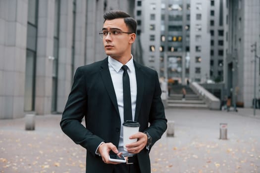 Busy man. Businessman in black suit and tie is outdoors in the city.