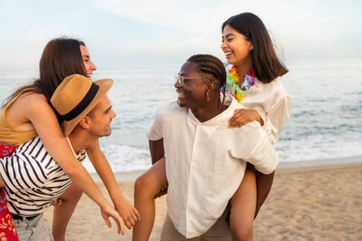Happiness and friendship. Young multiracial friends having fun outdoors in the beach near ocean. Piggy back ride. Lifestyle concept.