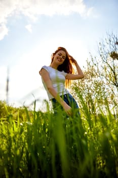 cute woman in summer clothes standing in a field of tall grass, bottom view. High quality photo