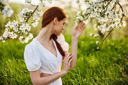 attractive fresh woman posing for a portrait of a flowering Apple tree and looks away. A vivid portrait in Sunny weather. High quality photo