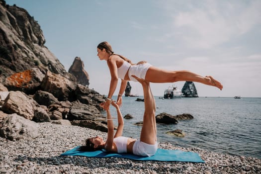 Woman sea yoga. Back view of free calm happy satisfied woman with long hair standing on top rock with yoga position against of sky by the sea. Healthy lifestyle outdoors in nature, fitness concept.