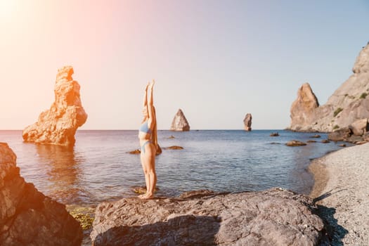 Middle aged well looking woman with black hair doing Pilates with the ring on the yoga mat near the sea on the pebble beach. Female fitness yoga concept. Healthy lifestyle, harmony and meditation.