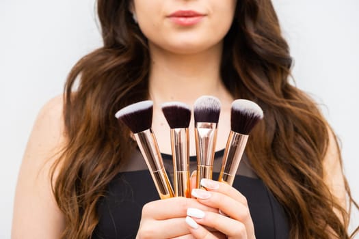 Woman holding makeup brushes in hands.