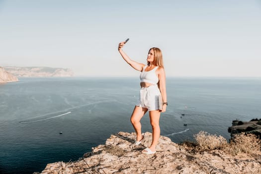 Woman travel sea. Young Happy woman in a long red dress posing on a beach near the sea on background of volcanic rocks, like in Iceland, sharing travel adventure journey