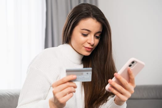 Young woman holding a credit card and using a mobile phone for paying. Online shopping and spending money for gifts concept.