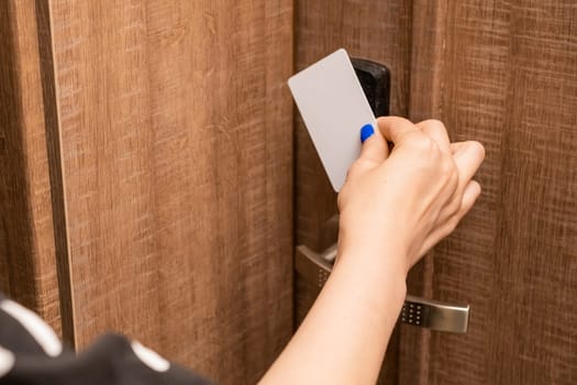 Woman hand puts key card to panel opening hotel room door. Female person with blue nails opening door