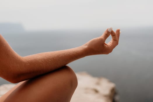 Middle aged well looking woman with black hair doing Pilates with the ring on the yoga mat near the sea on the pebble beach. Female fitness yoga concept. Healthy lifestyle, harmony and meditation.