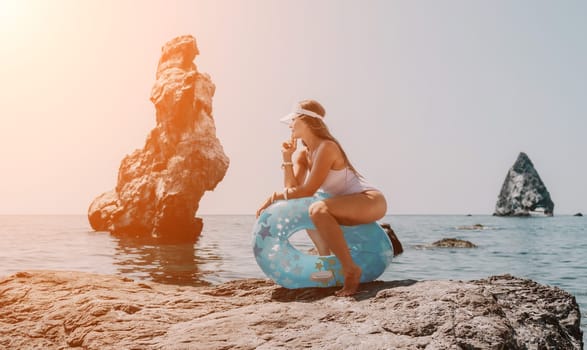 Woman summer sea. Happy woman swimming with inflatable donut on the beach in summer sunny day, surrounded by volcanic mountains. Summer vacation concept