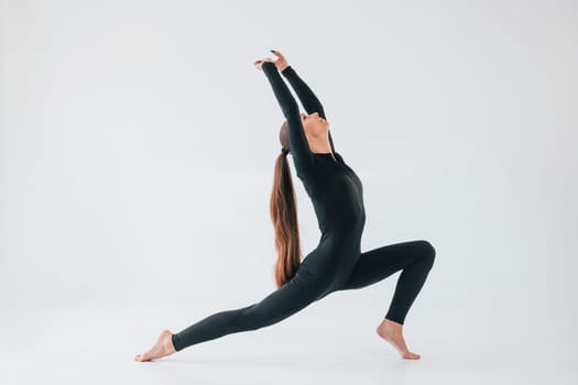 Professional exercises. Young woman in sportive clothes doing gymnastics indoors.