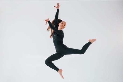 Professional exercises. Young woman in sportive clothes doing gymnastics indoors.