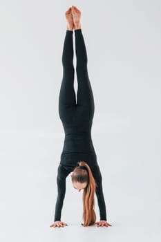 Professional exercises. Young woman in sportive clothes doing gymnastics indoors.