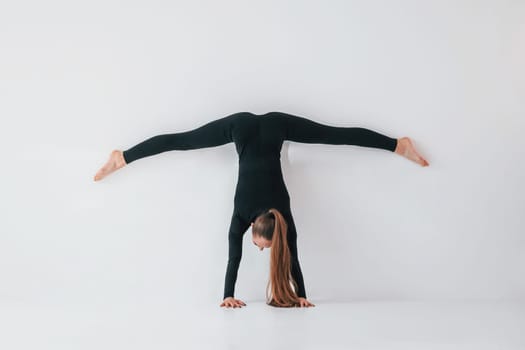 Practice routine. Young woman in sportive clothes doing gymnastics indoors.