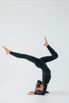 Practice routine. Young woman in sportive clothes doing gymnastics indoors.