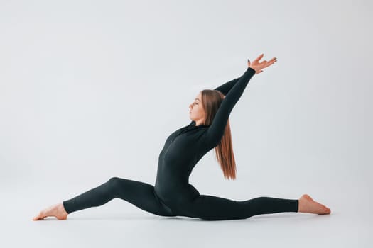 Side stretch. Young woman in sportive clothes doing gymnastics indoors.