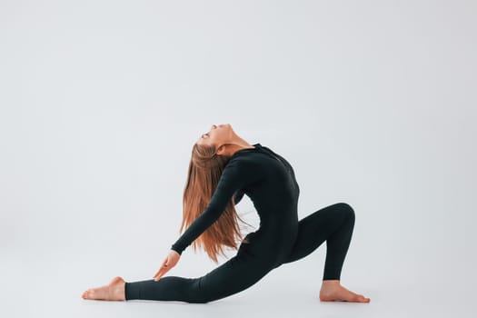 Side stretch. Young woman in sportive clothes doing gymnastics indoors.