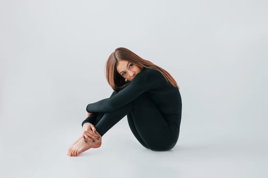 On the floor. Young woman in sportive clothes doing gymnastics indoors.
